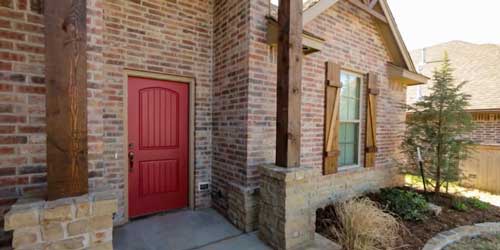 Outdoor shot of the front of a custom home with a red door, designed by Semco Construction